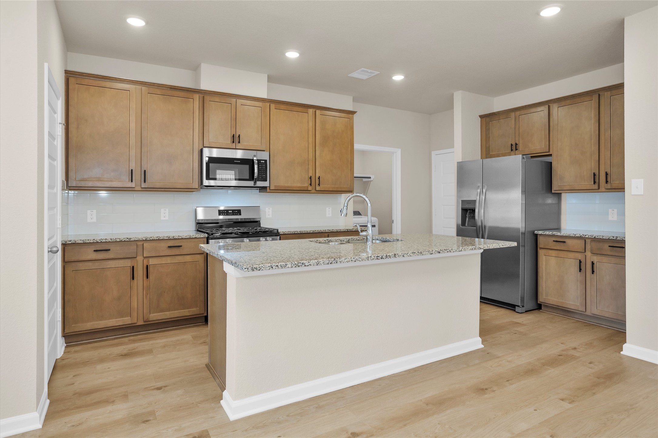 Kitchen features premium granite countertops, a large center island, and brand-new stainless steel appliances.