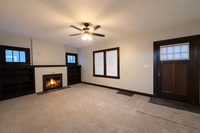 a view of an empty room with window and fire place