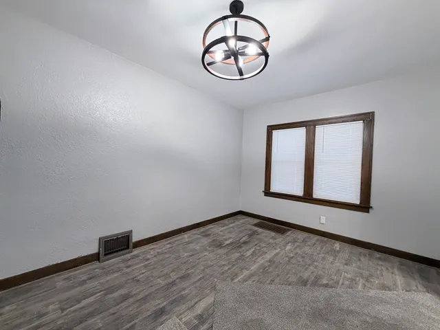 a view of an empty room with window and wooden floor