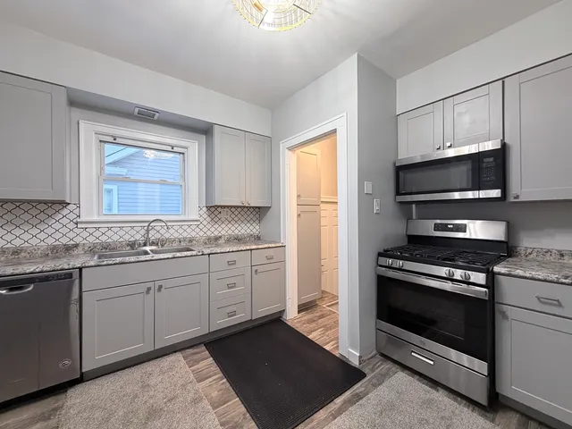 a kitchen with granite countertop a stove a sink and a microwave