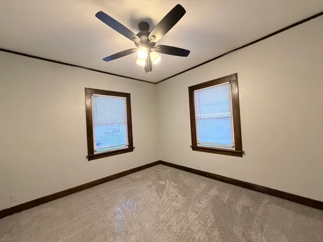 an empty room with windows and fan