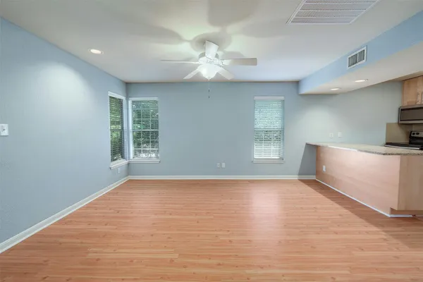 a view of a room with wooden floor and a ceiling fan