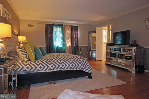 a bedroom with a bed and flat tv screen on the dresser