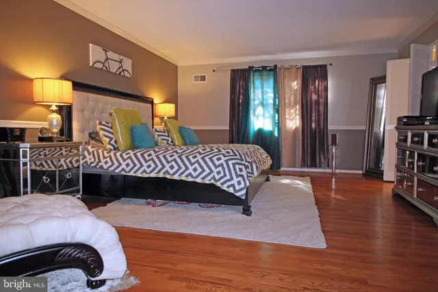 a bedroom with a bed lamps and a large mirror on dresser