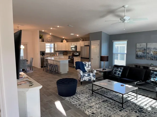 a living room with furniture kitchen view and a refrigerator