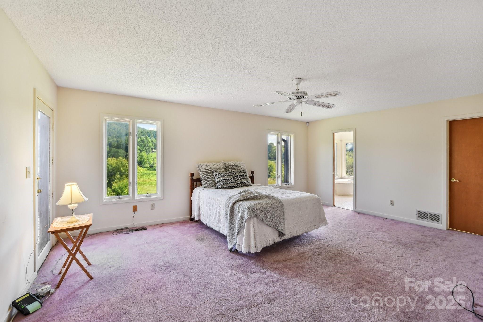 2281 Bearwallow Road Hendersonville, NC 28792 - Photo 16 of 46 a spacious bedroom with a bed and a chandelier