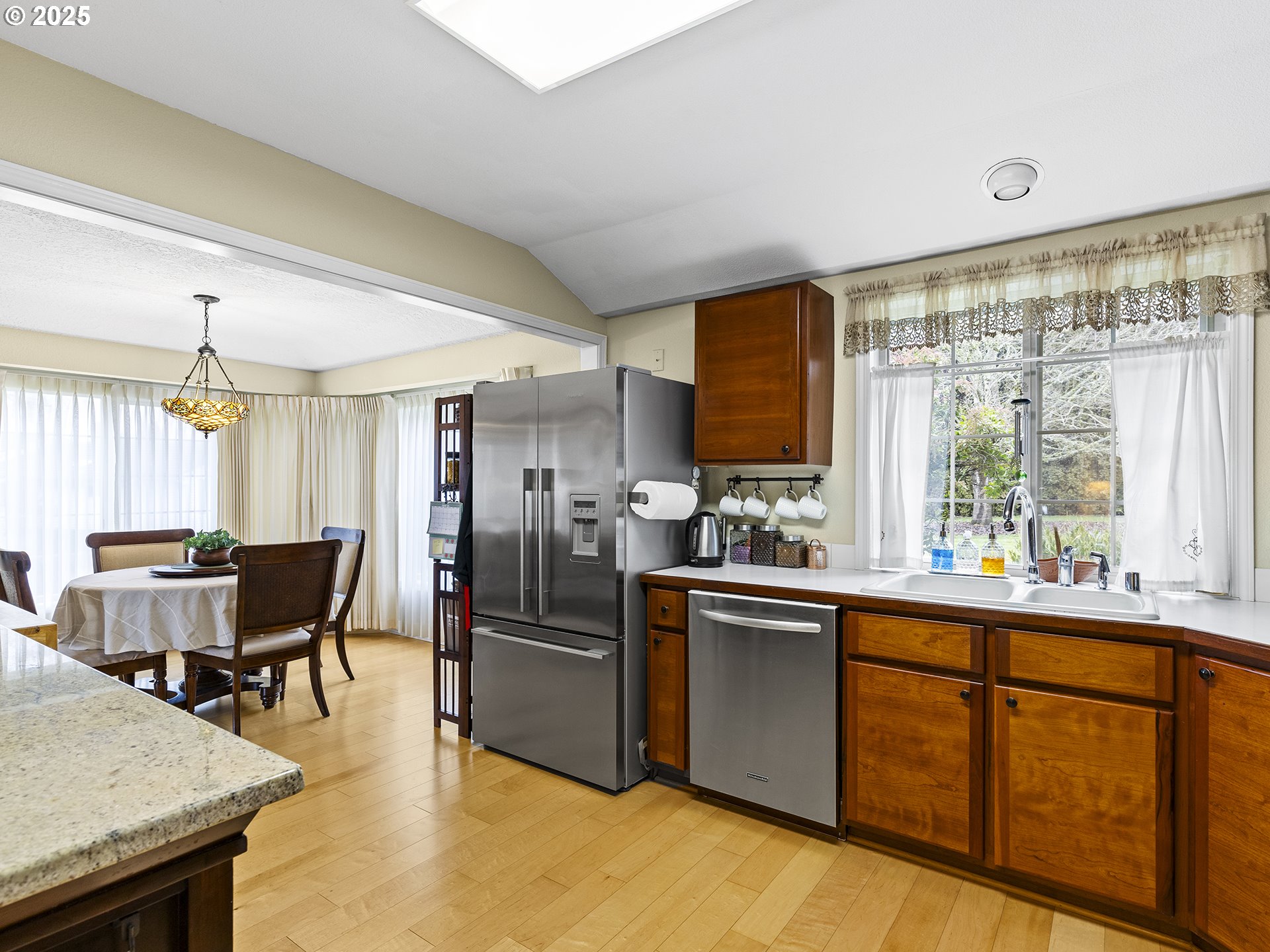 5906 Northwest 169th Street Ridgefield, WA 98642 - Photo 8 of 35 a kitchen with stainless steel appliances kitchen island granite countertop a table chairs and a refrigerator