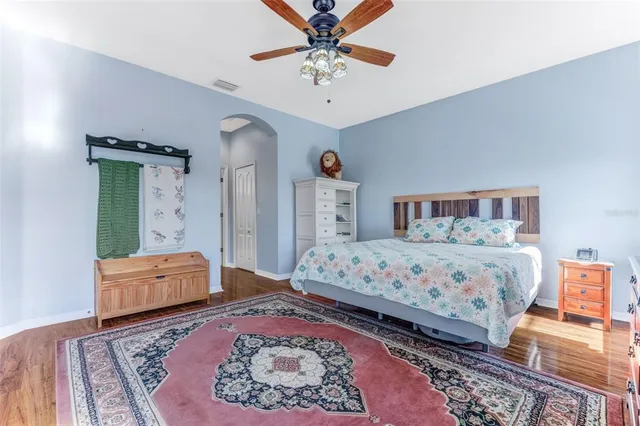 a bedroom with a bed and a dresser with wooden floor