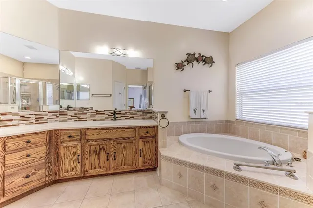 a spacious bathroom with a granite countertop double vanity sink a mirror a bathtub and shower