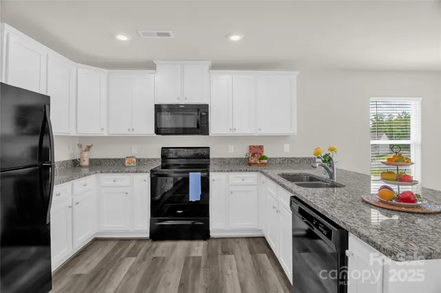 a kitchen with granite countertop a sink dishwasher stove and refrigerator with wooden floor