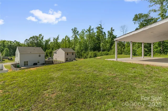 a backyard of a house with table and chairs plants and large tree