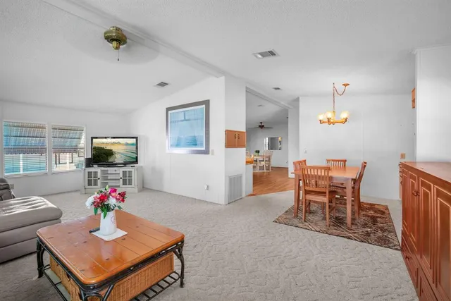 a living room with furniture kitchen view and a wooden floor