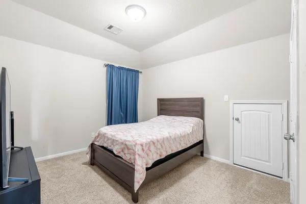 a bedroom with a bed and a flat tv screen on a dresser