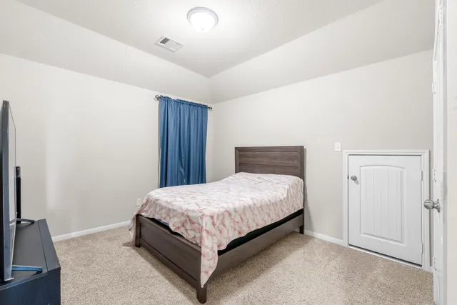 a bedroom with a bed and a flat tv screen on a dresser