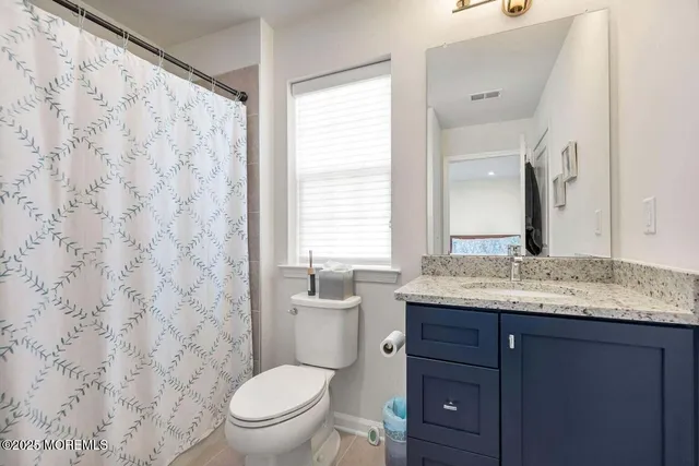 a bathroom with a granite countertop sink a toilet and a mirror