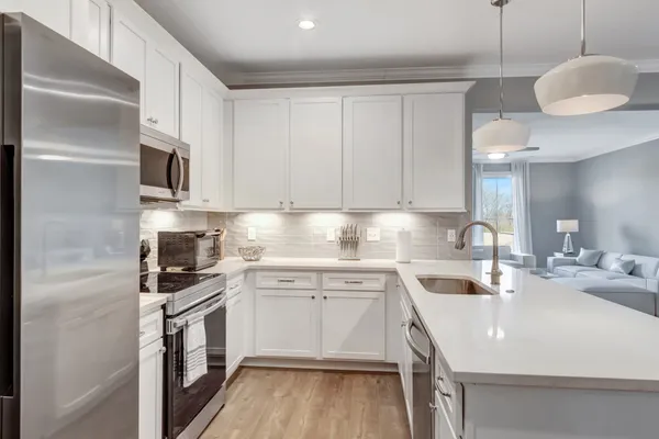a kitchen with a sink dishwasher and white cabinets with wooden floor