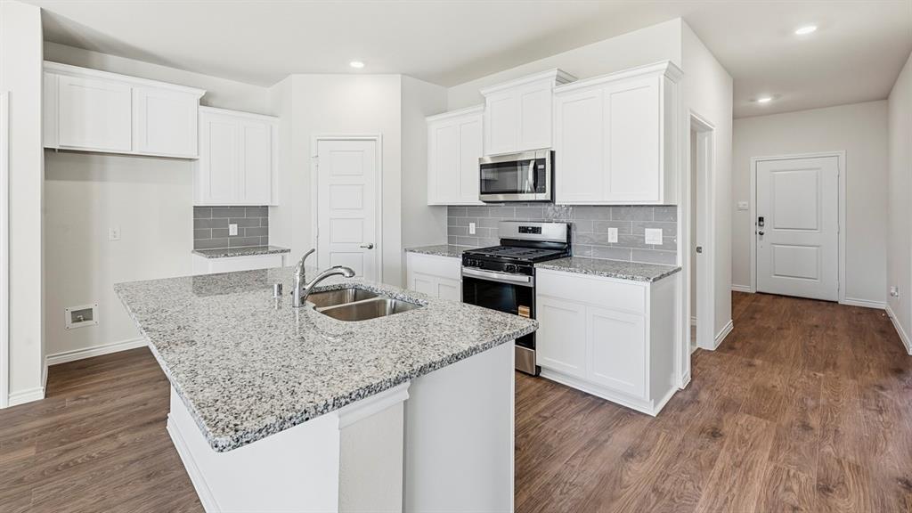 403 Flintlock Road Caddo Mills, TX 75135 - Photo 22 of 26 Kitchen with stainless steel appliances, white cabinetry, tasteful backsplash, dark wood finished floors, and recessed lighting