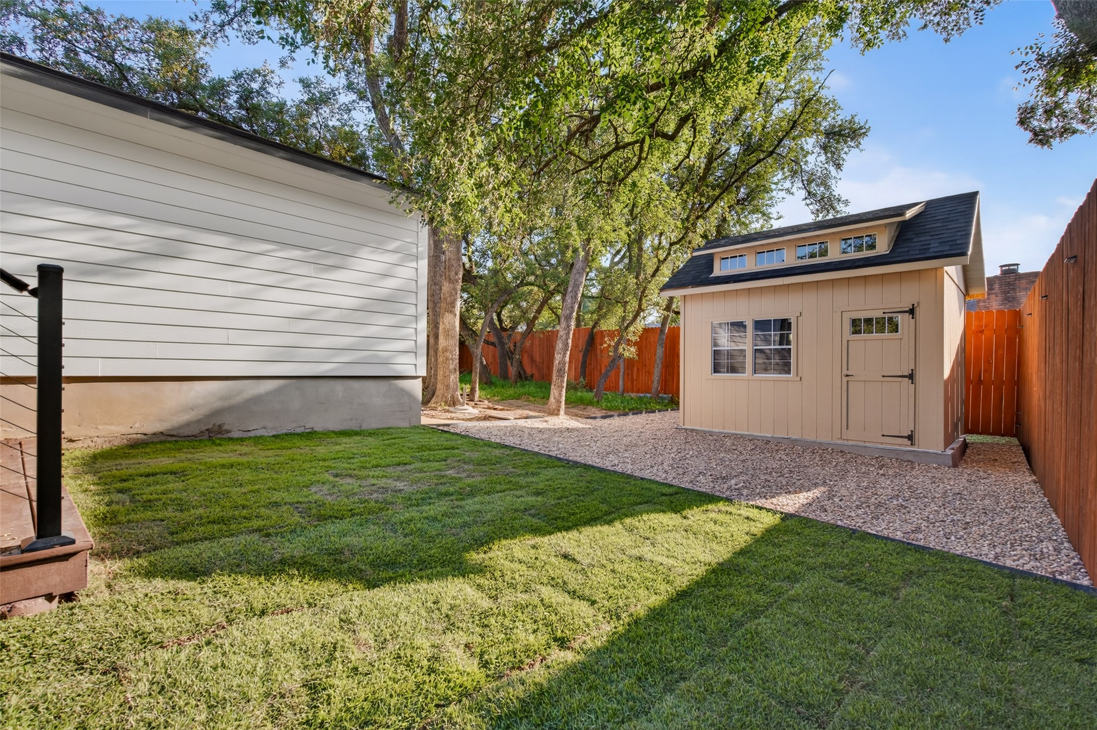 6806 Rearden Road Austin, TX 78745 - Photo 22 of 28 Mature trees shade a neat lawn and gravel pathway leading to a detached backyard shed.