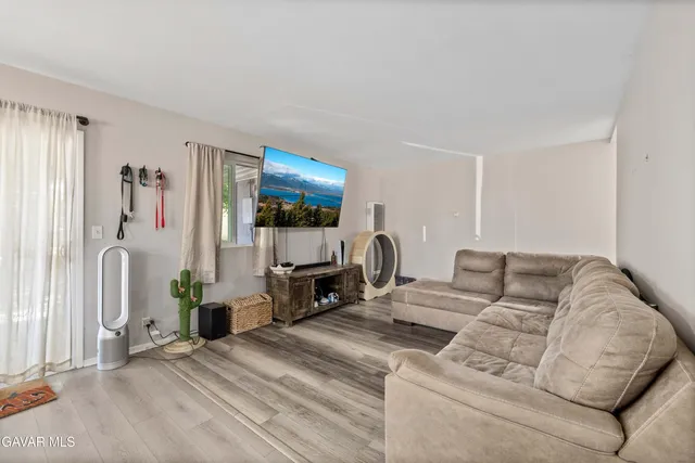 a living room with furniture a flat screen tv and a refrigerator