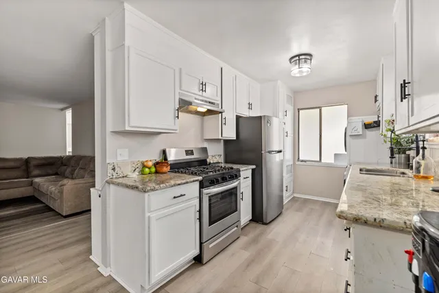 a kitchen with granite countertop a sink stove and refrigerator