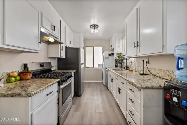 a kitchen with stainless steel appliances granite countertop a stove a sink and a refrigerator