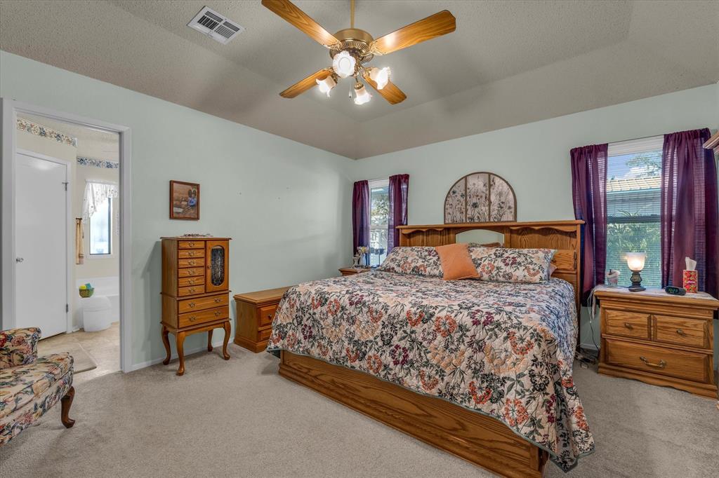 107 Fort Graham Circle Waco, TX 76705 - Photo 18 of 39 Bedroom with light colored carpet, a ceiling fan, vaulted ceiling, and connected bathroom