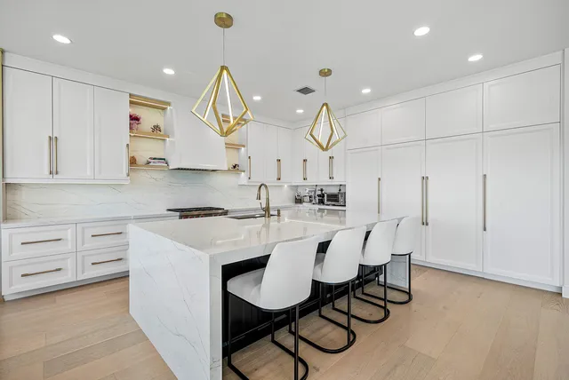 a kitchen with stainless steel appliances kitchen island a table chairs sink and cabinets