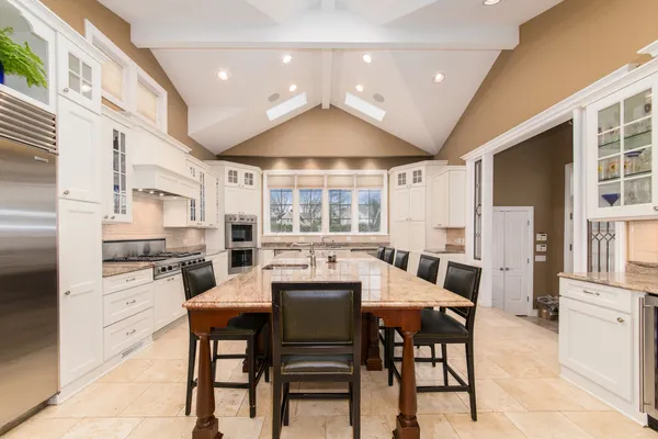 a dining room with stainless steel appliances kitchen island granite countertop a table chairs and a refrigerator
