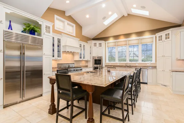a kitchen with stainless steel appliances kitchen island granite countertop a table chairs and a refrigerator
