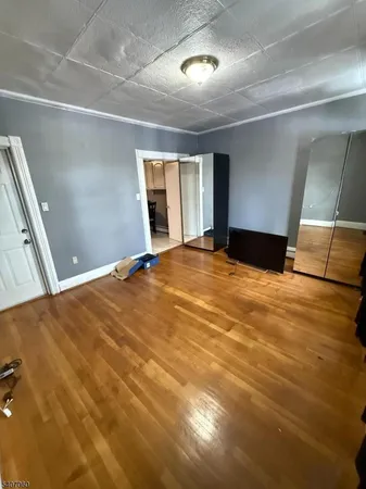 a view of an empty room with window and wooden floor