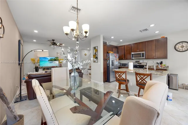 a view of a dining room with furniture a kitchen and chandelier