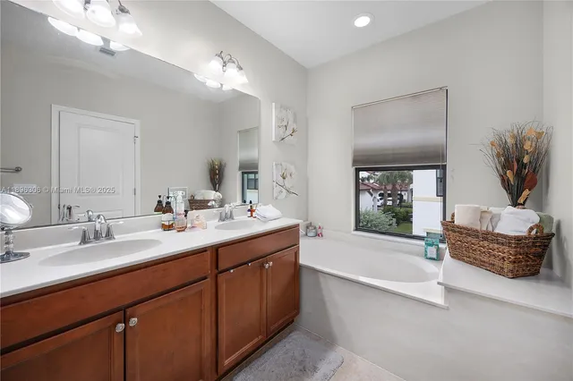 a spacious bathroom with a granite countertop sink a large mirror and a bathtub