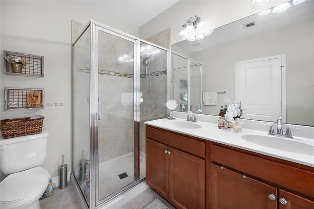 a bathroom with a double vanity sink toilet mirror and shower