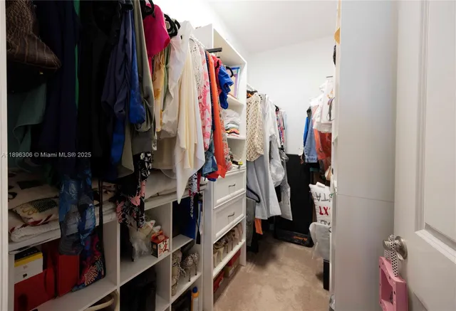 a view of walk in closet with clothes and shoes