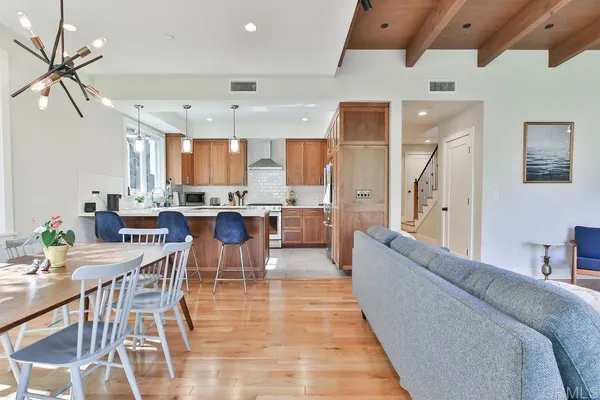a living room with stainless steel appliances furniture and a kitchen view