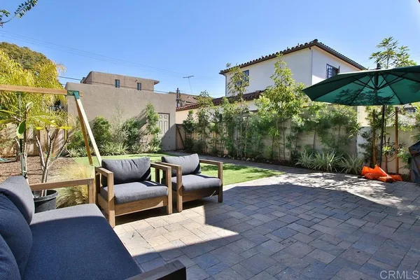 a view of a patio with couches table and chairs under an umbrella with a fire pit