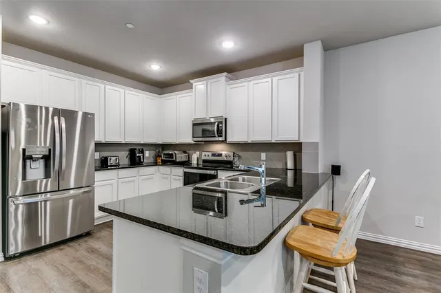 a kitchen with stainless steel appliances granite countertop a refrigerator a stove a sink a dining table and chairs