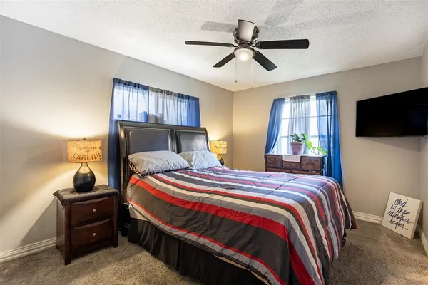 a bedroom with a bed a dresser and a flat screen tv