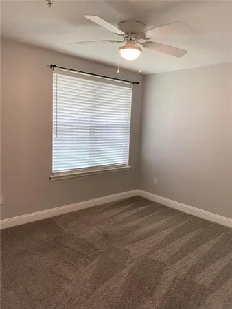 an empty room with a window and a fan