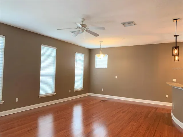 a view of an empty room with window and wooden floor