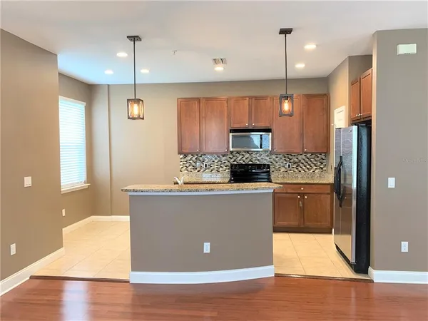 a kitchen with stainless steel appliances granite countertop a refrigerator a sink a stove and a wooden floors