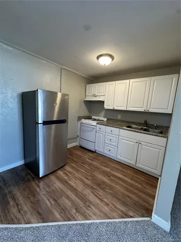 a kitchen with granite countertop a refrigerator and a stove top oven