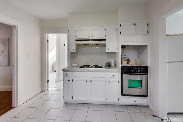 a kitchen with white cabinets and a stove with refrigerator