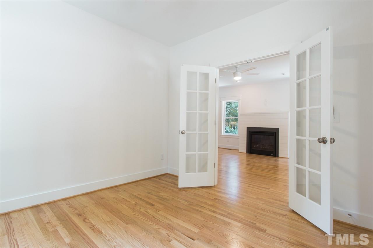 5316 Russell Road Durham, NC 27712 - Photo 6 of 25 an empty room with wooden floor fireplace and windows
