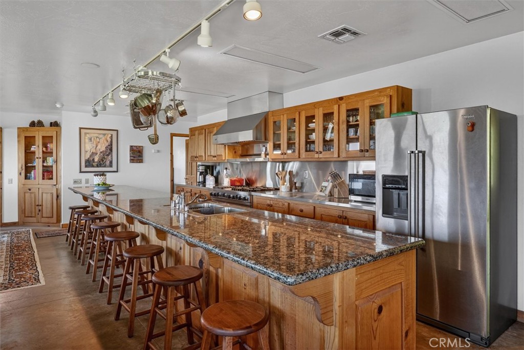 5851 Mt Bullion Ridge Road Mariposa, CA 95338 - Photo 14 of 58 a kitchen with stainless steel appliances granite countertop a table chairs and a refrigerator