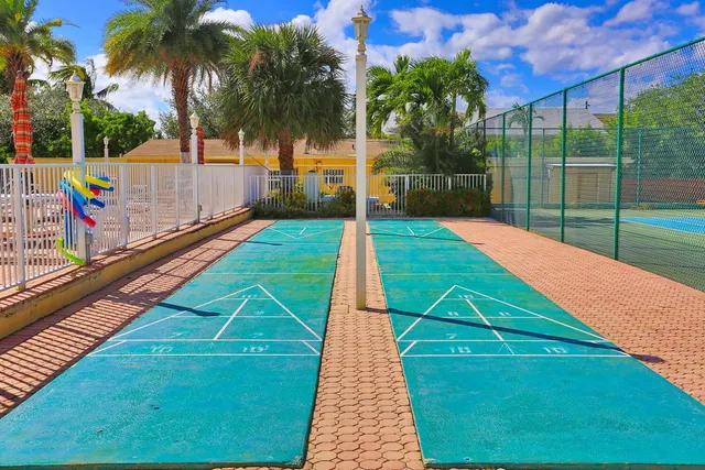 a view of a swimming pool with a yard and palm trees