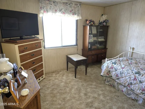 a room with lots of white furniture a chandelier and a window