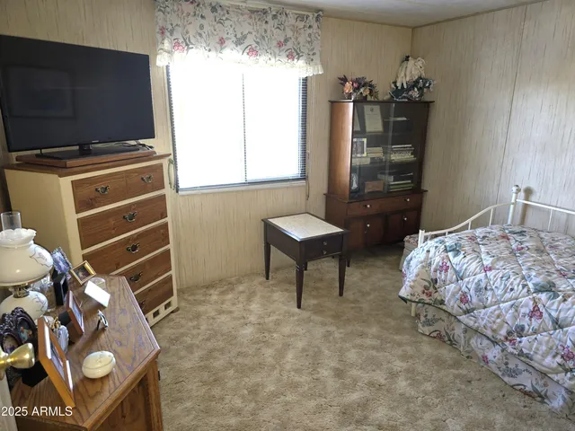 a room with lots of white furniture a chandelier and a window