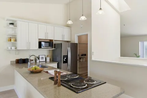 a kitchen with stainless steel appliances granite countertop a stove a refrigerator a sink a stove and white cabinets