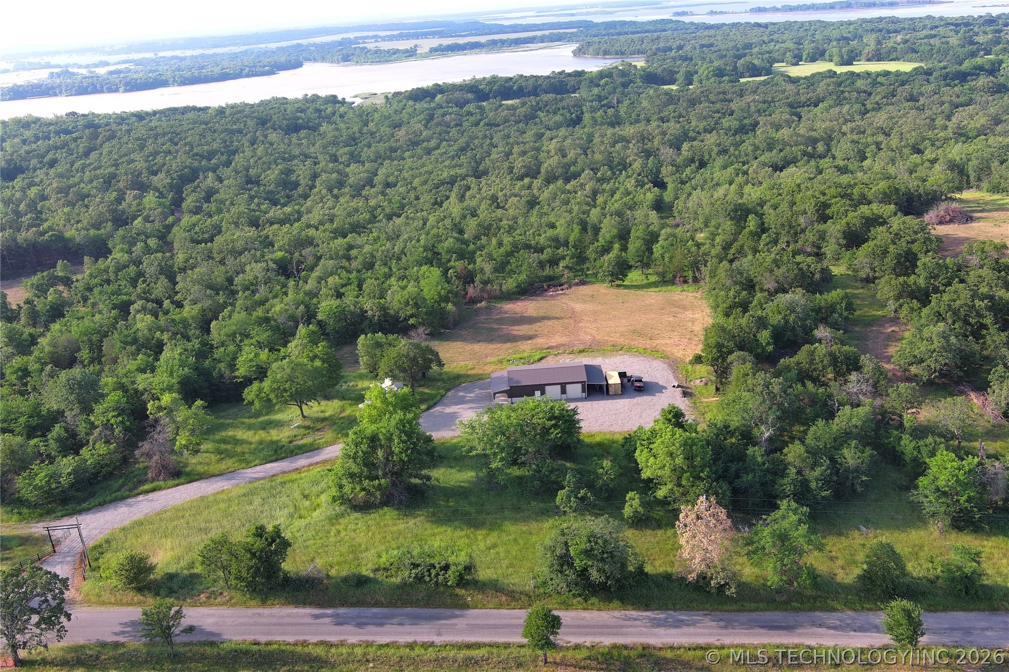 20862 East 1160th Road Keota, OK 74941 - Photo 1 of 47 Expansive wooded acreage featuring a single-story structure, gravel driveway, and a paved road frontage